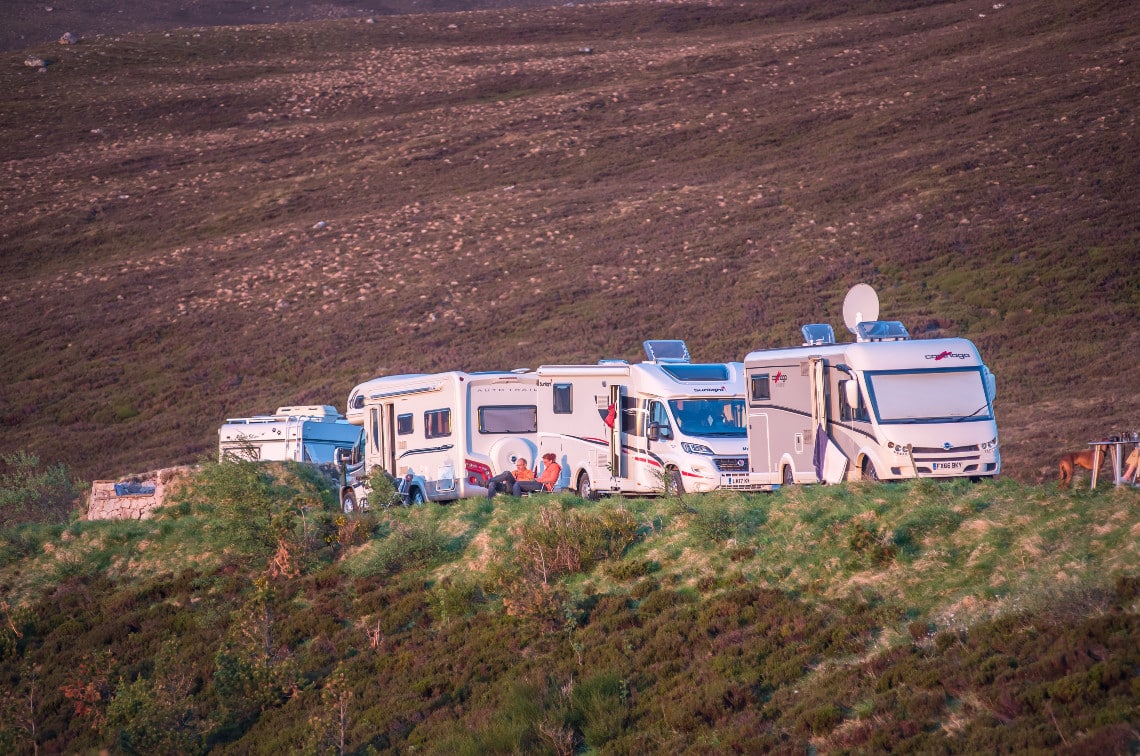 a row of campervans parked on country road 