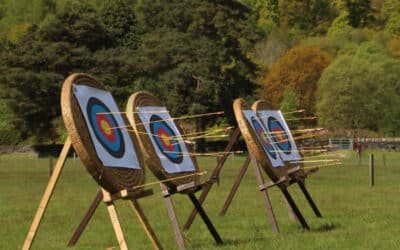 3 archery targets lined up with lots of arrows sticking in them