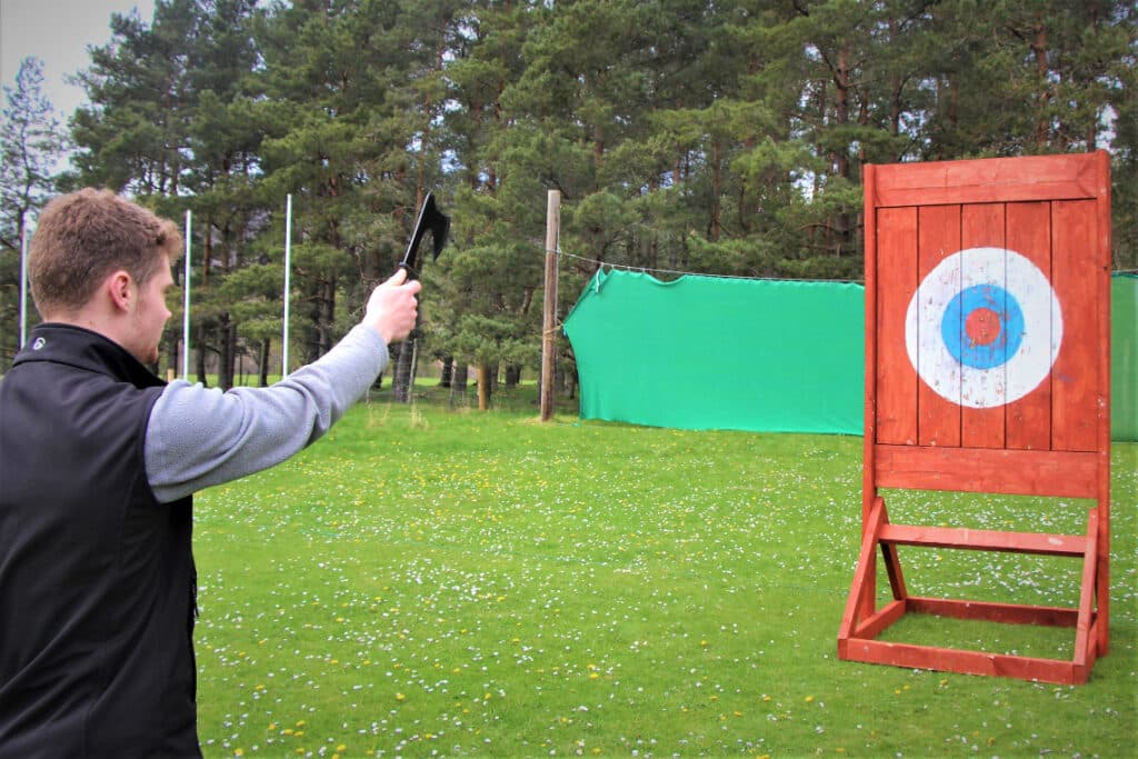 A man lines up to throw axes at targets during an axe-throwing activity session