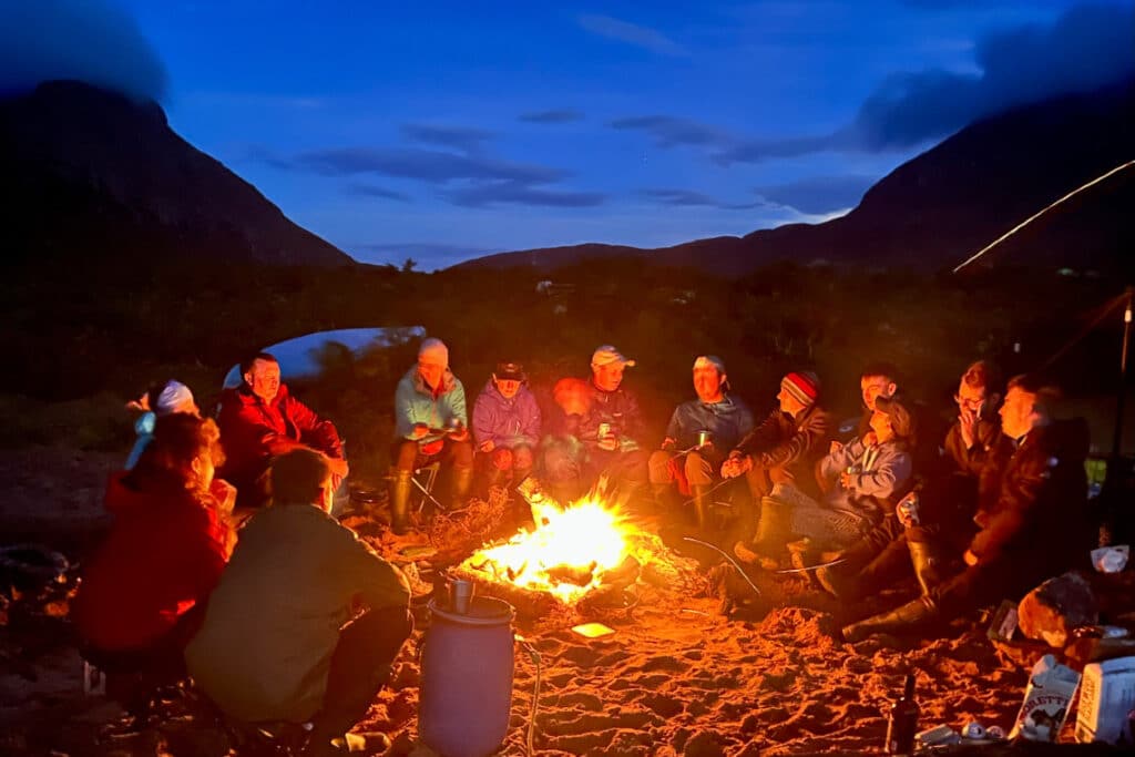 a group sit around a campfire in the dark chatting