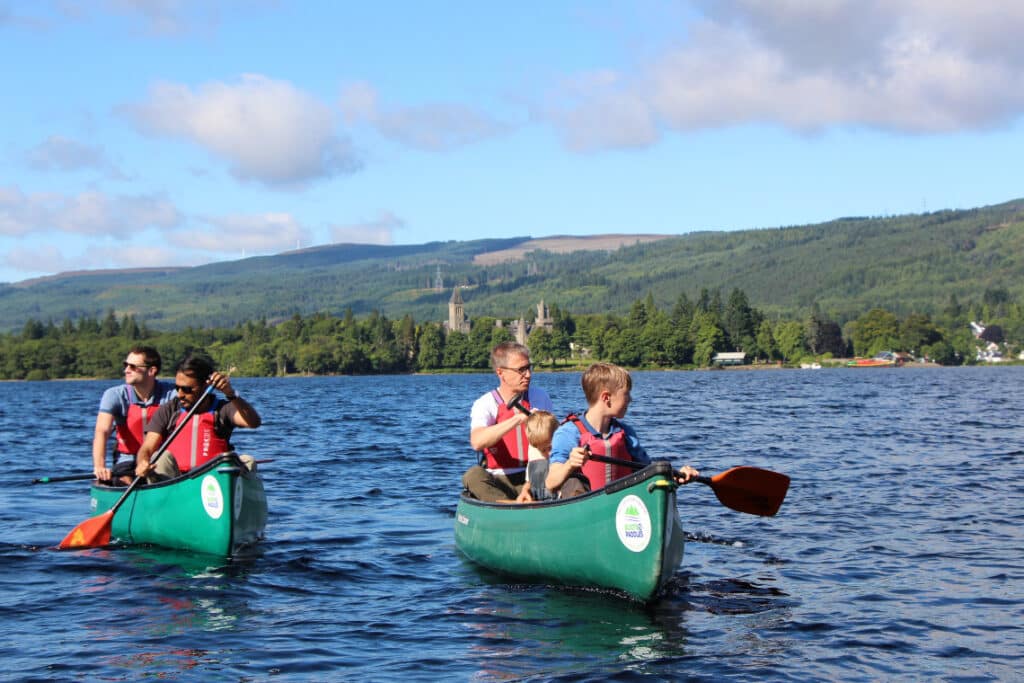 A family group canoeing on a scottish loch on a sunny day