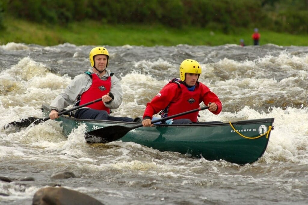 2 men canoeing river rapids