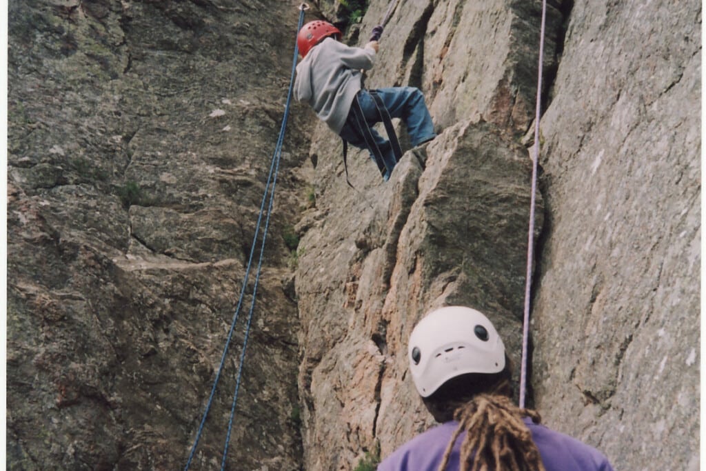 person rock climbing with another person belaying