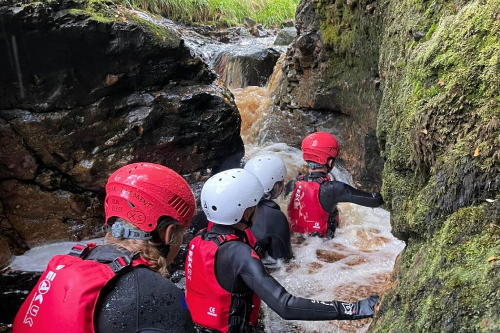 A group of people scrable through a river gorge while on a gorge walking experience