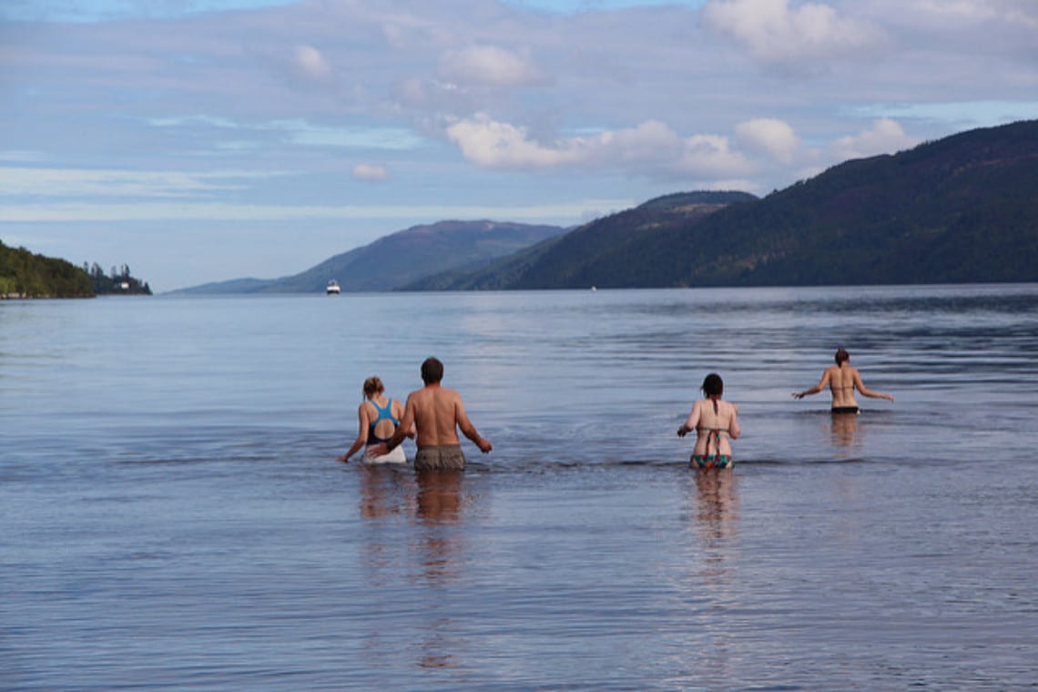 a group of people wading into loch ness for a swim