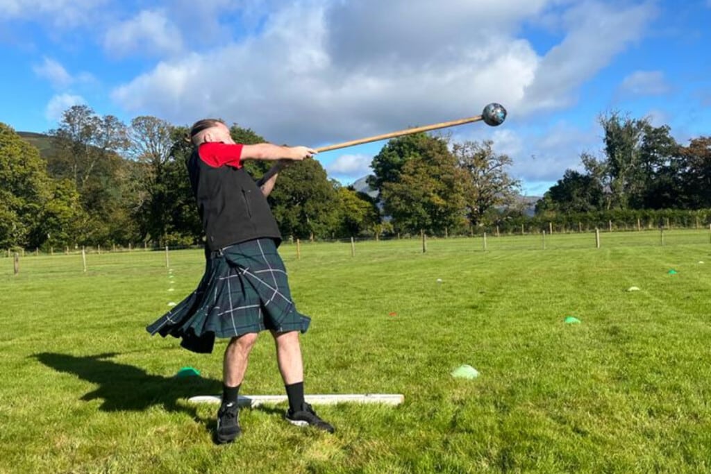 a kilted man throwing a scot's hammer as part of a mini highland games experience