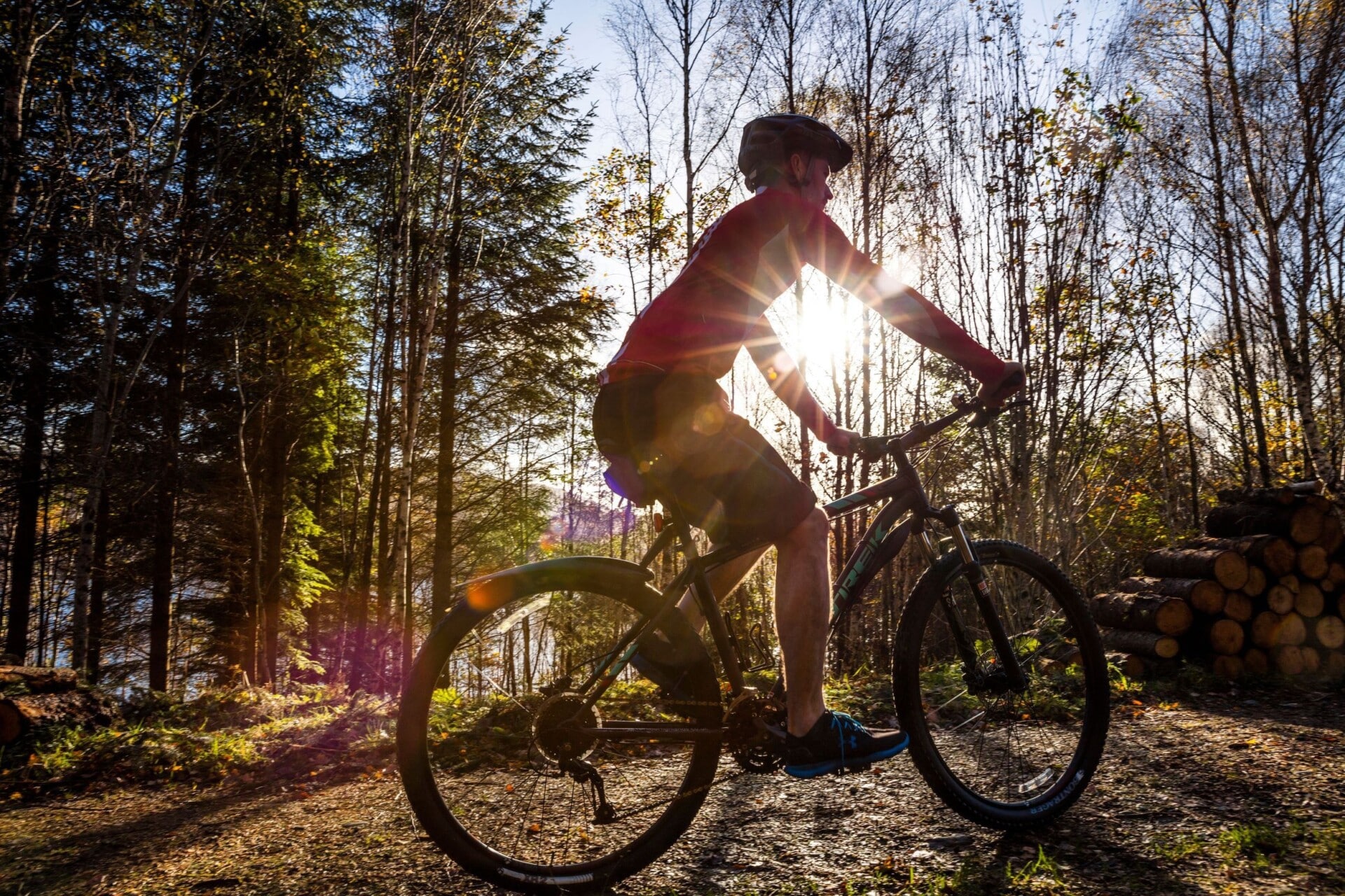 a person riding a mountain bike on a forest trail with the sun low in the back ground resulting in a silhouette