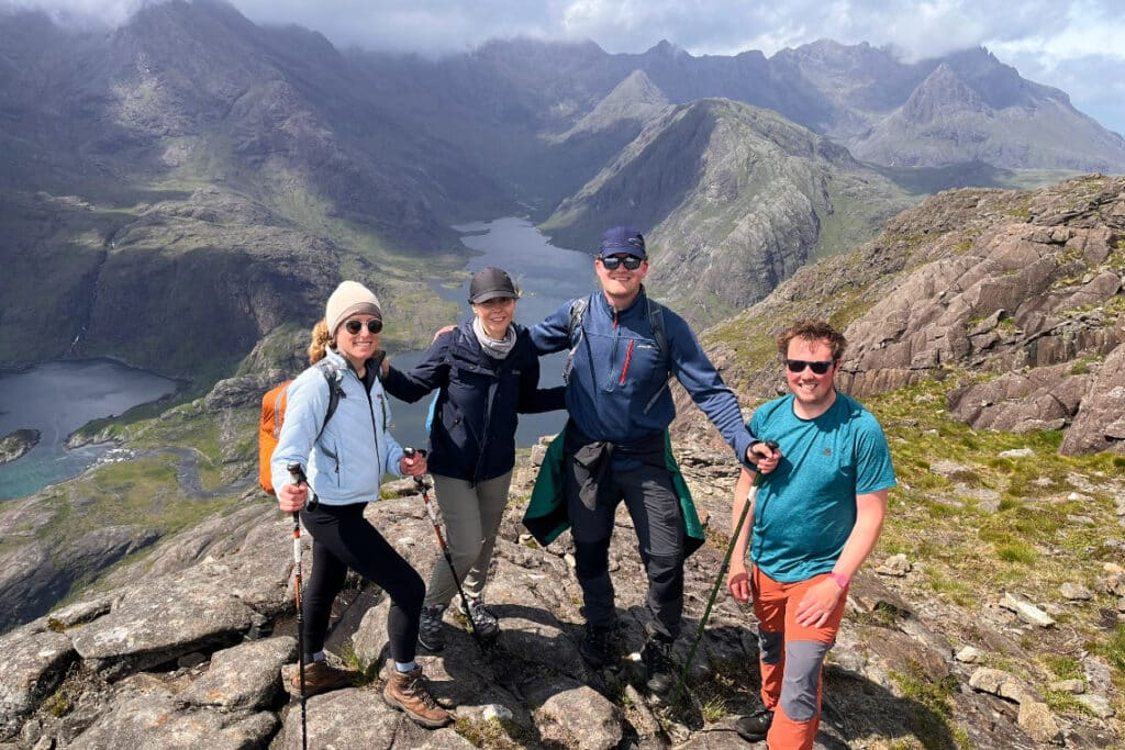 group at the top of mountain sgurr na stri in skye. beautiful backdrop of loch coruisk and the black cuillin mountains