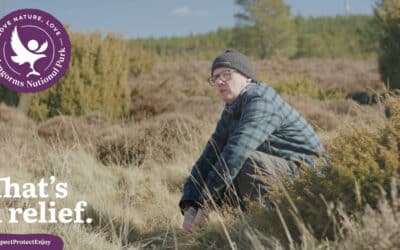 A man squats behind a bush in the Cairngorms National Park, answering the call of nature