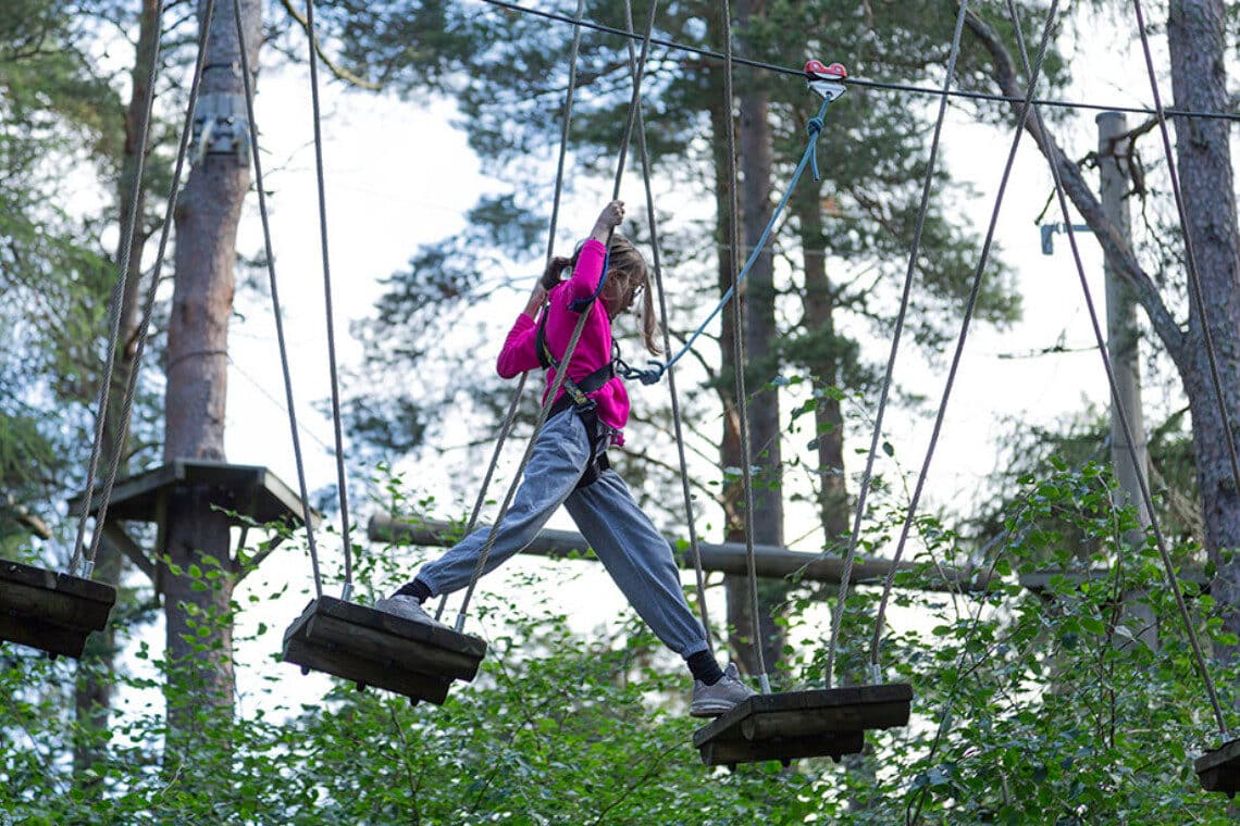 Someone making their way across a wobbly bridge at TreeZone Aviemore