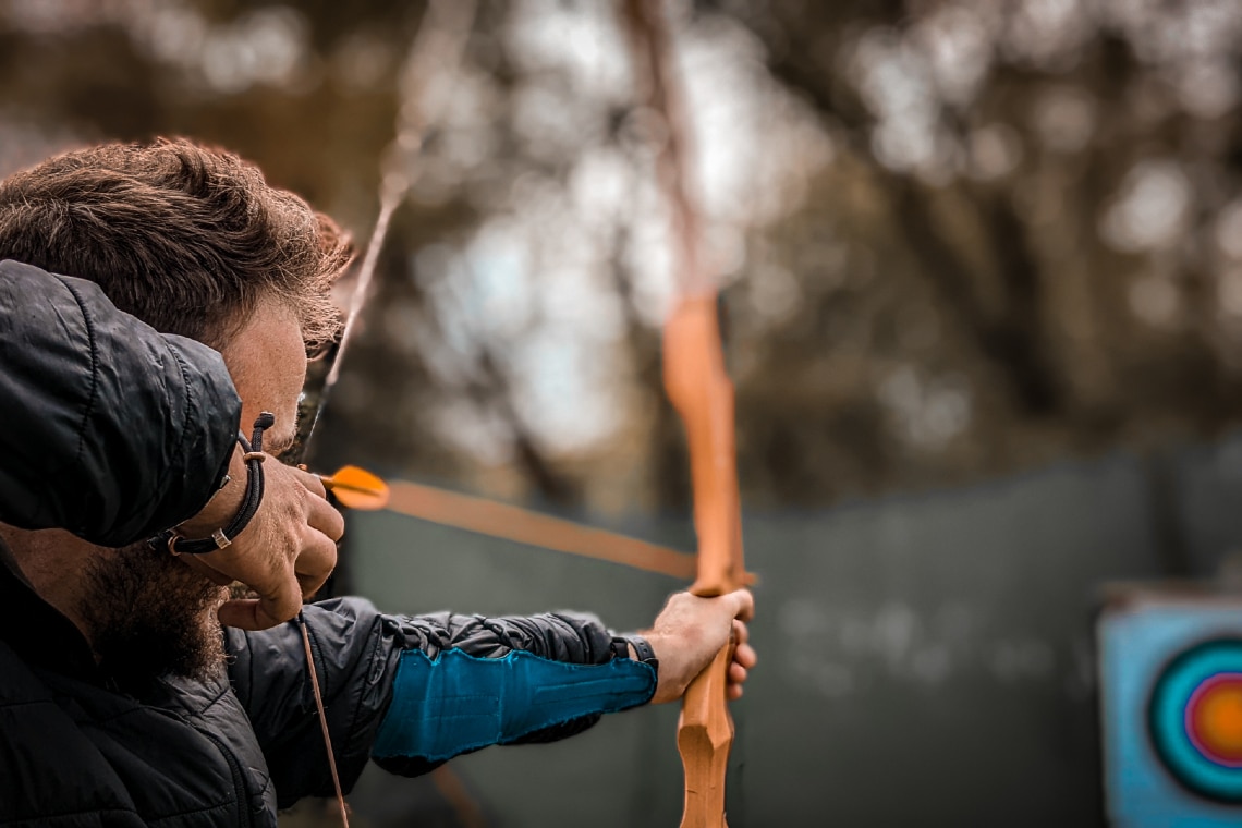 man aiming bow and arrow