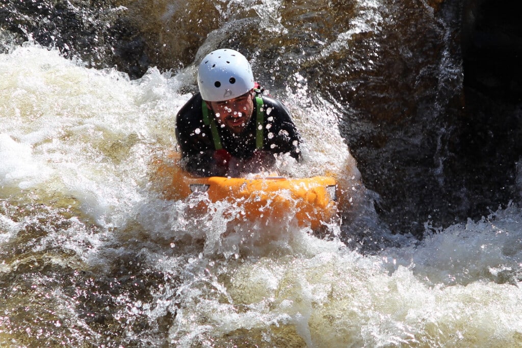 person riding rapids while white water river sledging