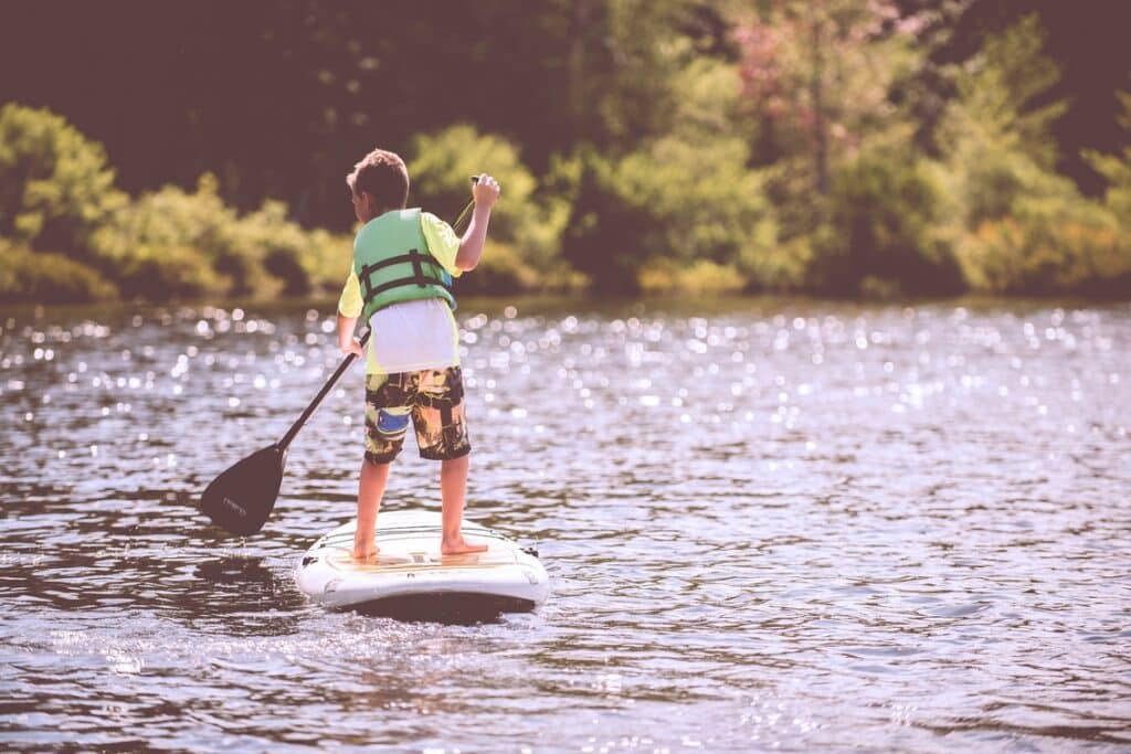 young boy paddleboarding on a calm loch